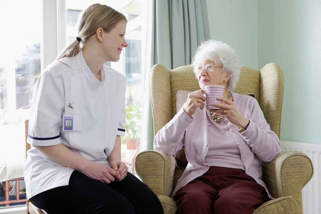 young nurse chatting with senior woman in care home