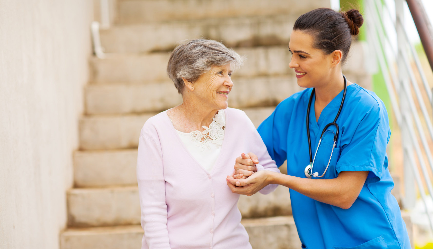 caregiver helping senior woman walking down stairs